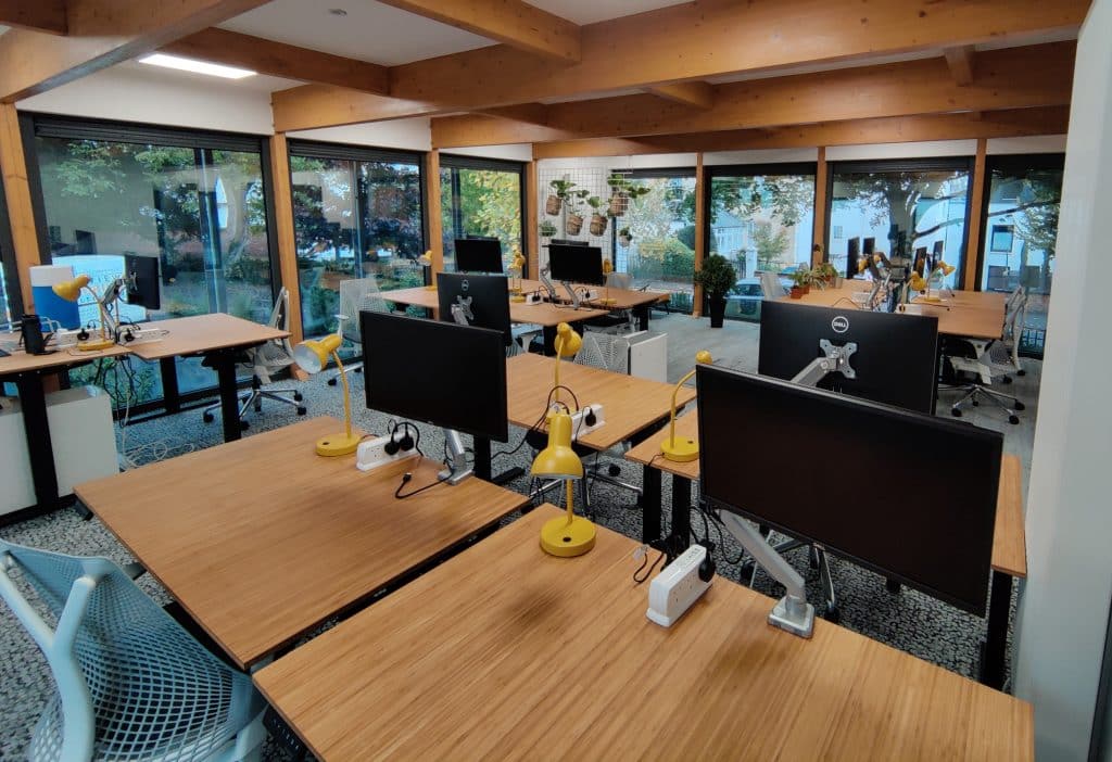 Coworking space at Star Lodge, used for the free coworking week promotion. With Herman Miller chairs, bamboo desks, and monitors, and exposed rustic beams in the ceiling.